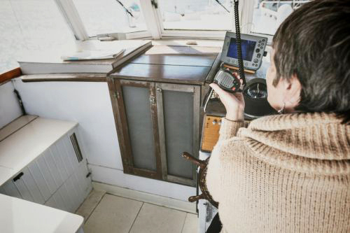 Woman on boat using VHF radio.