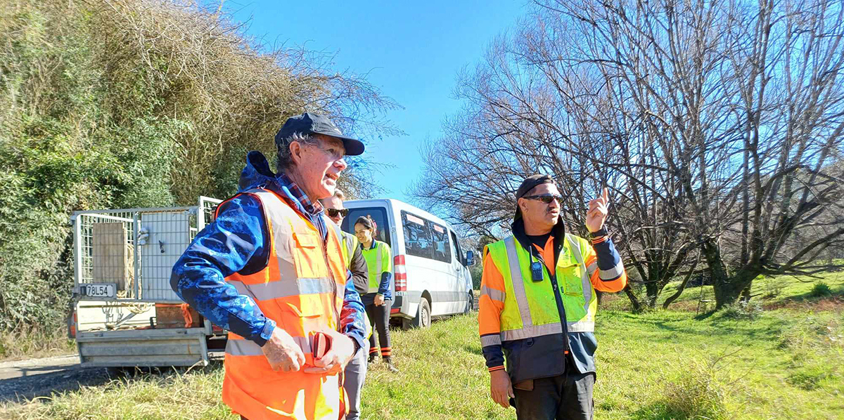 Men wearing hi-vis in a paddock.