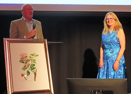 Man with a microphone and woman on a stage.