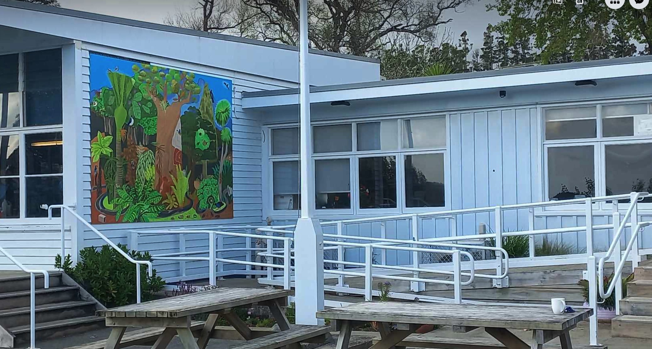 Canvas of trees, plants and wildlife mounted to the side of school building.