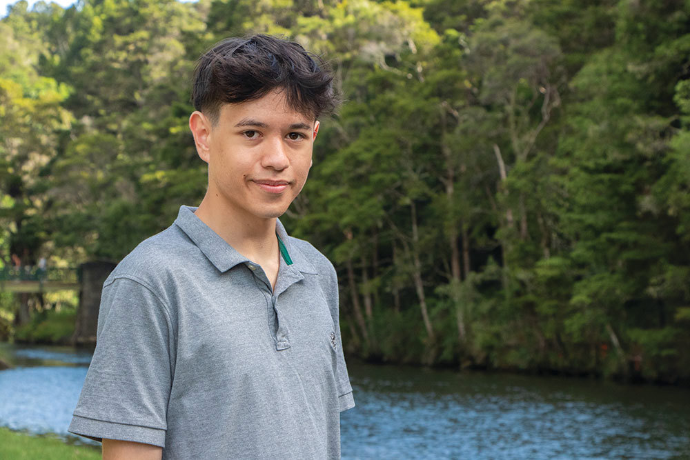 Young man standing on a river bank.